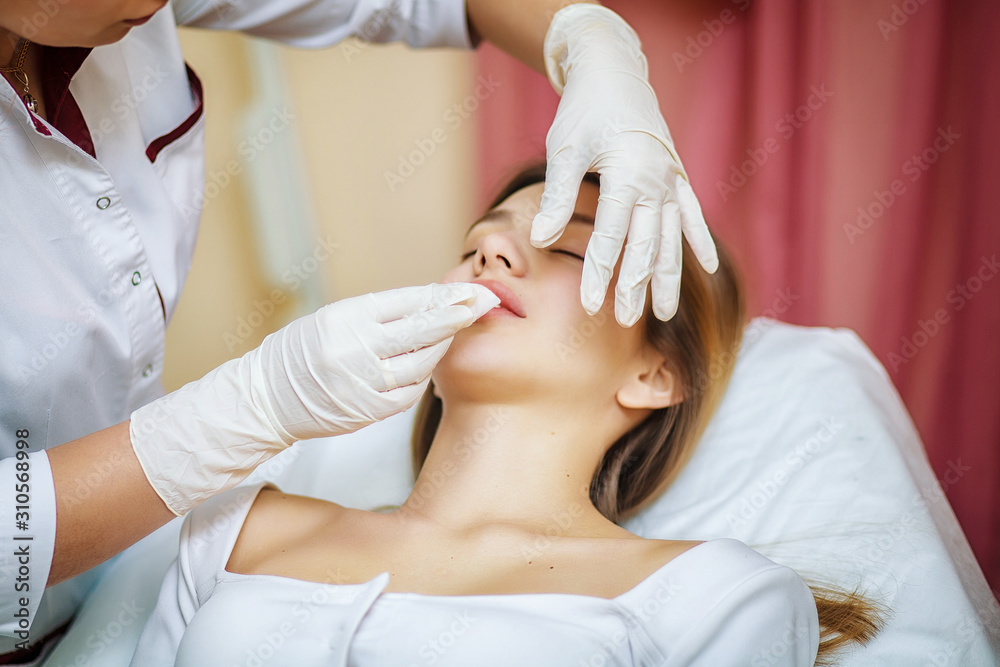 Obraz premium Young pretty woman receiving treatments in beauty salons. Young beautiful woman in the office beautician lying on the couch. Contouring procedure , revitalization. Beauty injections .