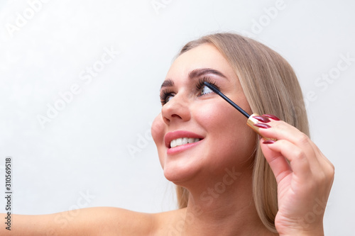 woman applying make up  paint her eyelashes  for a evening date in front of a mirror