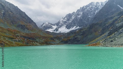 Drone fly above ripple shiny turquoise water of Kuyguk lake towards snowy range photo