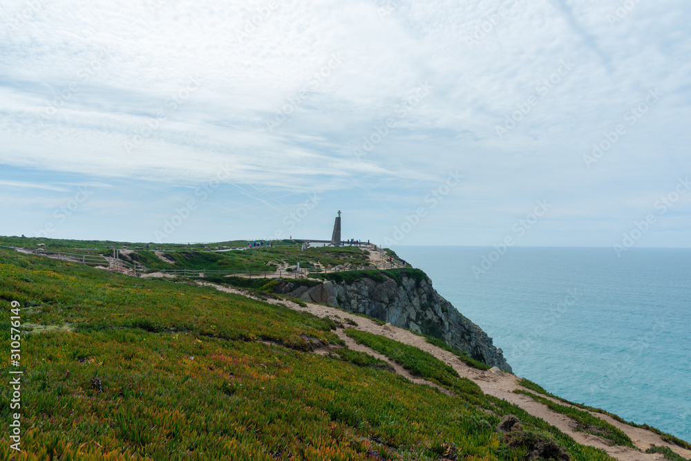 Monument with the cross on it at Cabo da Roca (Cape Roca) the westernmost  extent of mainland Portugal, continental Europe and the Eurasian land mass. Bright vivid landscape of European country.