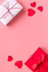 Present to a lover on Valentine's Day. Gift boxes near paper hearts on pink background top-down frame copy space