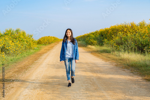 Portrait of happy Asian woman enjoying and relaxing at Tree Marigold or yellow flowers national garden park during travel holidays vacation trip outdoors at Mae Moh, Lumpang, Thailand. Lifestyle. photo