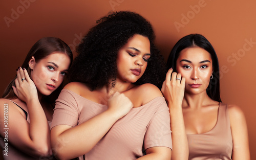 young pretty asian, caucasian, afro woman posing cheerful together on brown background, lifestyle diverse nationality people concept