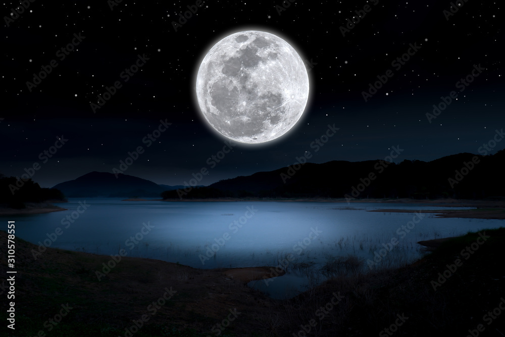 Super full moon over lake in the dark night.