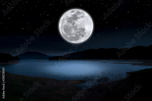 Super full moon over lake in the dark night. © Onkamon