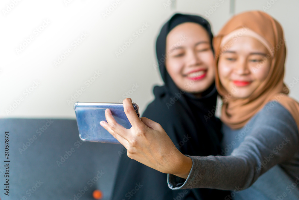Two Malay friends wearing hijab at the sofa