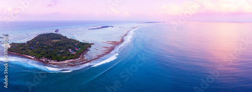 Waves breaking at sunset over Maldivian surf island photo