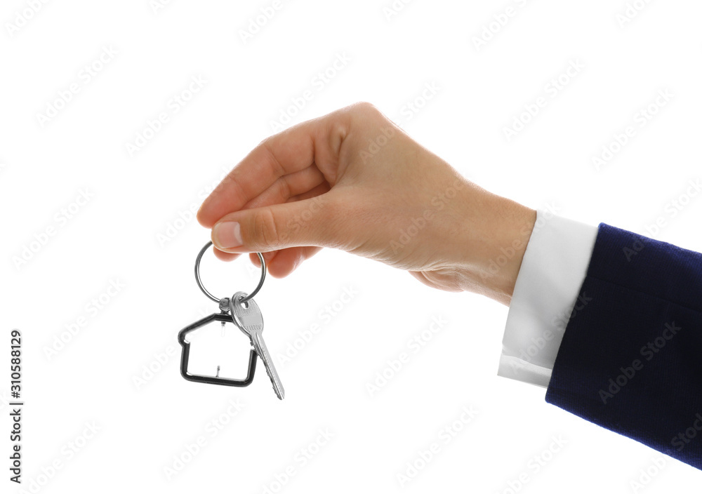 Real estate agent holding house key with trinket on white background, closeup Real estate agent holding house key with trinket on white background, closeup