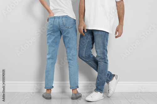 Couple in stylish jeans near light wall, closeup