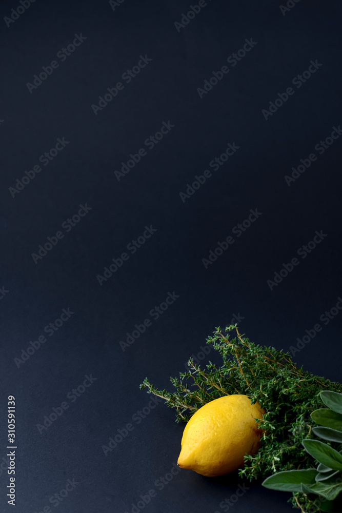 Lemon with herbs on black background. Copy space, minimal style, healthy lifestyle