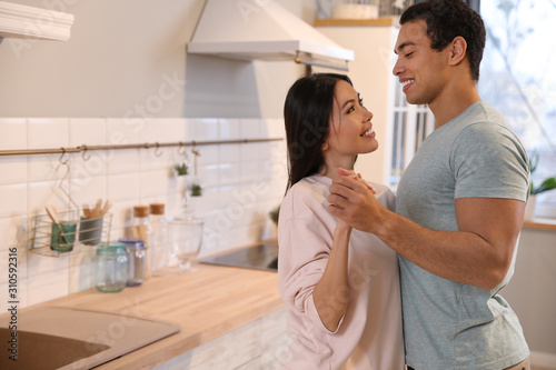 Lovely young interracial couple dancing at home. Space for text © New Africa