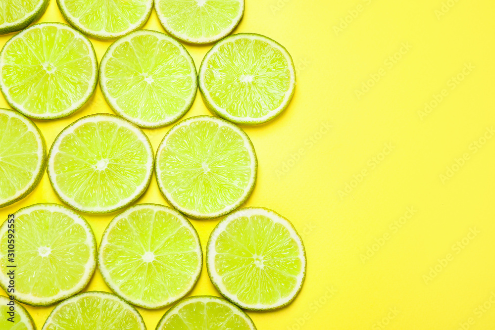 Juicy fresh lime slices on yellow background, flat lay. Space for text