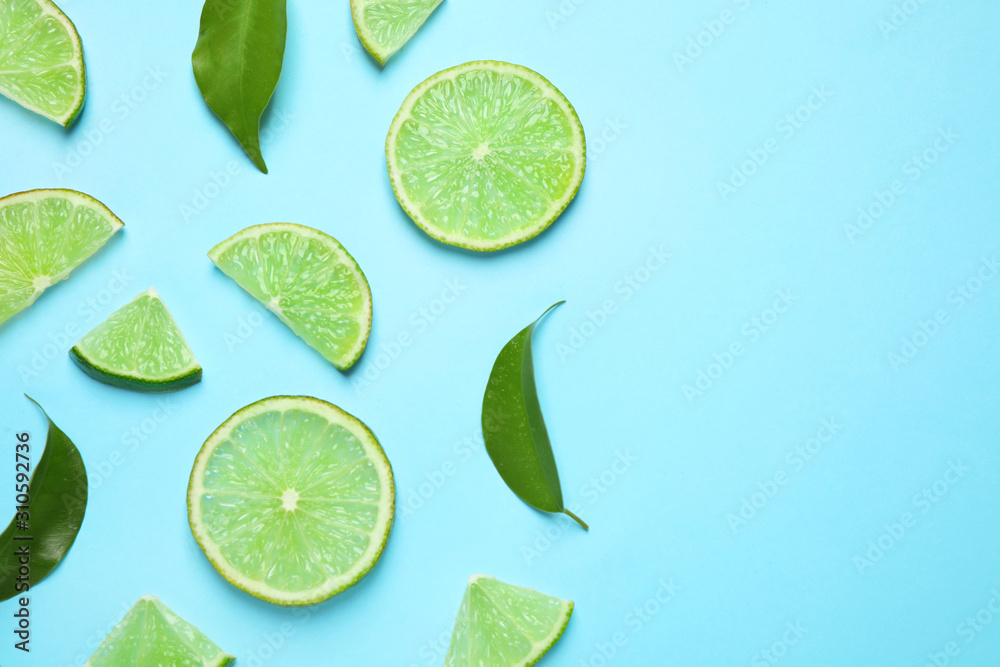 Juicy fresh lime slices and green leaves on light blue background, flat lay. Space for text