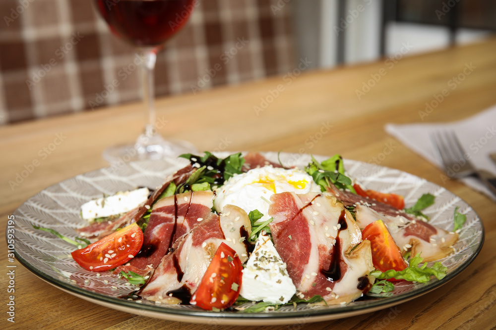 Delicious prosciutto salad with vegetables served on wooden table indoors Delicious prosciutto salad with vegetables served on wooden table indoors