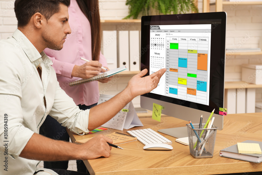 Colleagues working with calendar app on computer in office