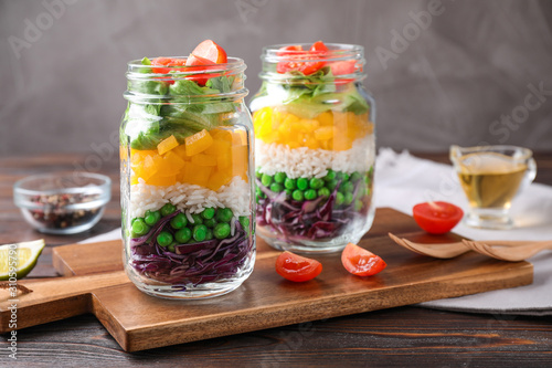 Healthy salad in glass jars on wooden table