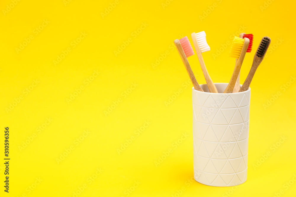 Toothbrushes made of bamboo in holder on yellow background. Space for text Toothbrushes made of bamboo in holder on yellow background. Space for text