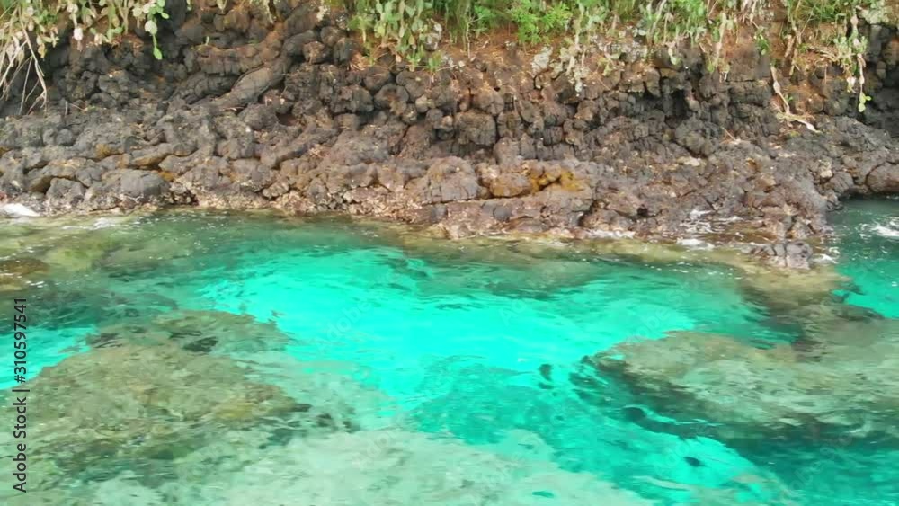 Drone fly close above wavy blue water surface showing volcanic rocky shoreline Drone fly close above wavy blue water surface showing volcanic rocky shoreline