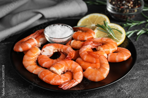 Delicious cooked shrimps with salt and lemon on dark grey table