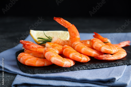 Delicious cooked shrimps with rosemary and lemon on slate board