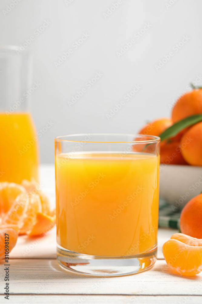Glass of fresh tangerine juice and fruits on white wooden table Glass of fresh tangerine juice and fruits on white wooden table