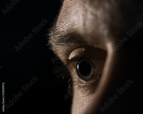 Closeup of a green human eye with dilated pupils on a black background