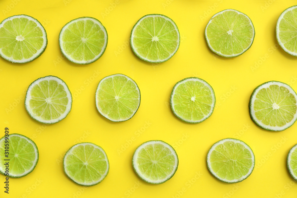 Slices of fresh juicy limes on yellow background, flat lay