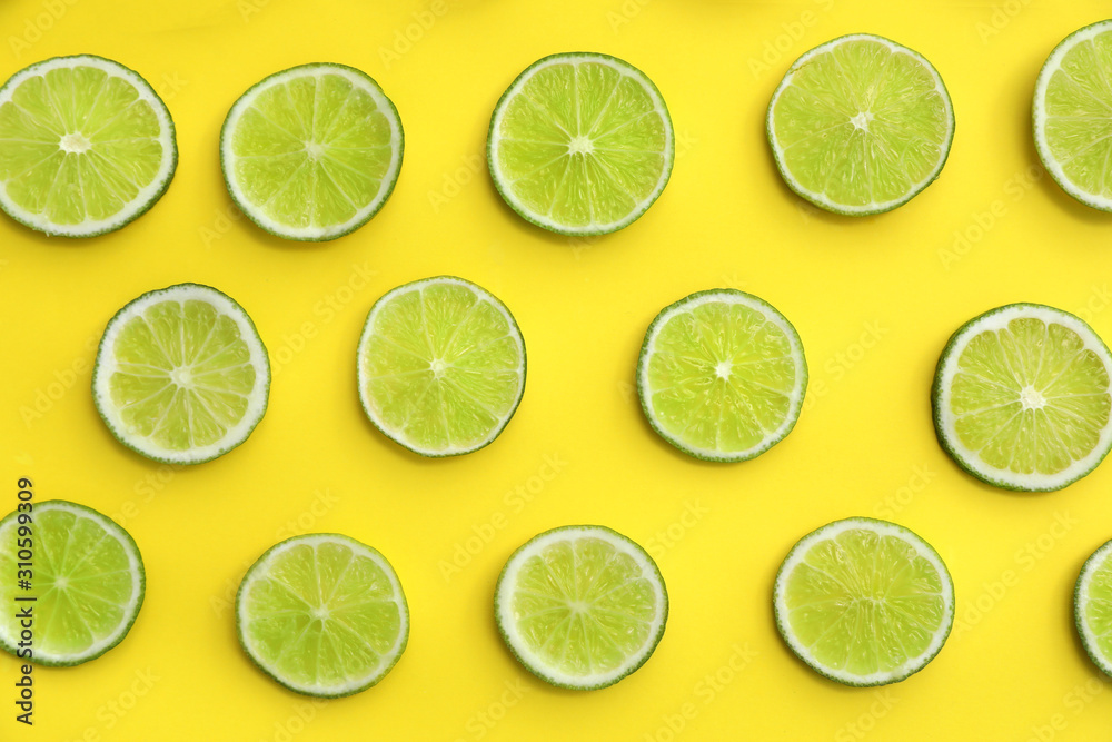 Slices of fresh juicy limes on yellow background, flat lay Slices of fresh juicy limes on yellow background, flat lay