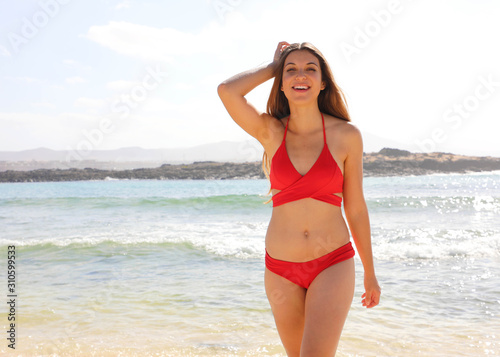 Beautiful young bikini woman standing at sea beach in Fuerteventura, Canary Islands