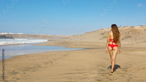 Sexy beautiful young woman walking on empty tropical beach
