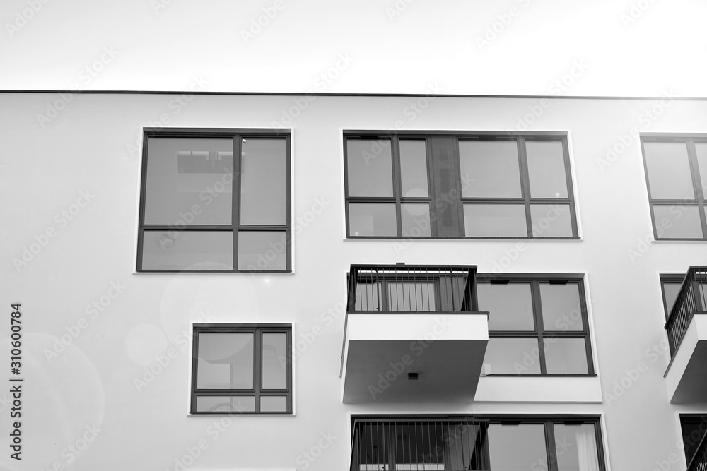 Fototapeta premium Sun rays light effects on urban buildings. Fragment of modern residential apartment with flat buildings exterior. Detail of new luxury house and home complex. Black and white.