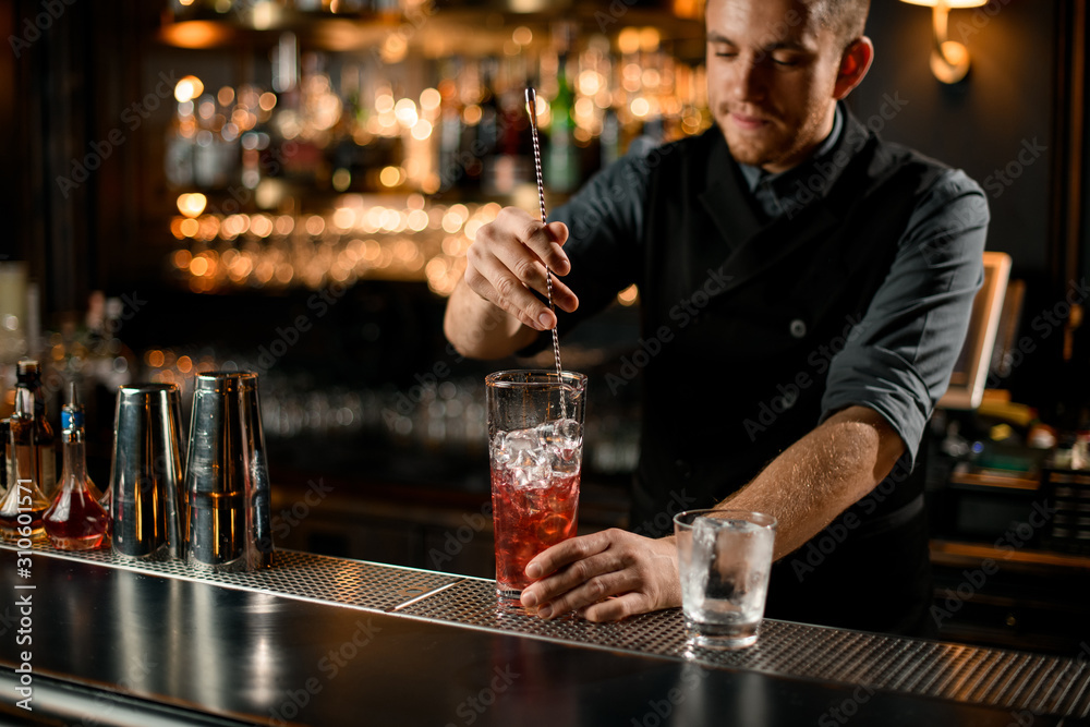 Bartender stirring alcohol drink with a bar spoon