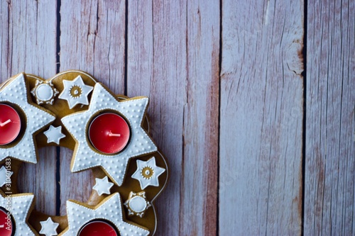 Christmas decorative advent wreath of gingerbread stars with candles on wooden background and copy space