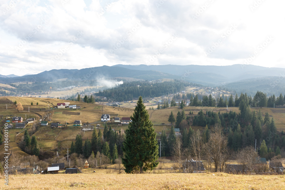 Fototapeta premium The wonderful landscape of the foggy mountain and forest and the small village under it