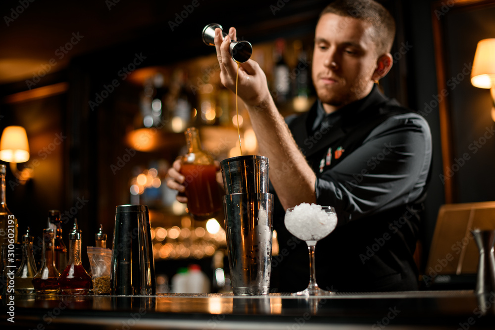Bartender flowing liquor from jigger to shaker