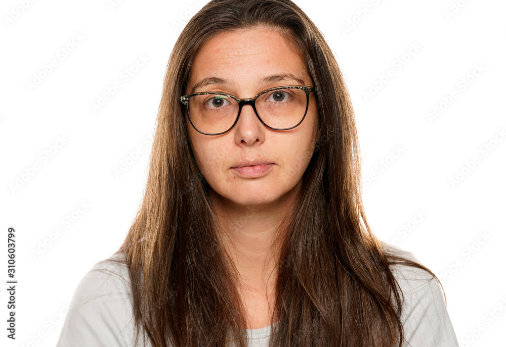 Portrait of young serious woman with glasses and  without makeup on white background