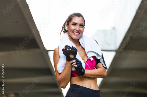 Young sporty woman putting on her training gloves. Woman Doing Workout Exercises On Street. Beautiful Athletic Fit Girl Stretching And Relaxing After Fitness Training © Graphicroyalty