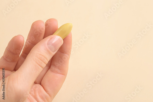 Closeup view of woman holding suppository on beige background, space for text. Hemorrhoid treatment photo