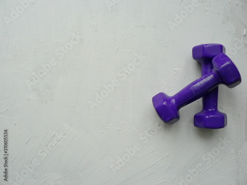 Two purple dumbbells on a white textured background with space for your text.