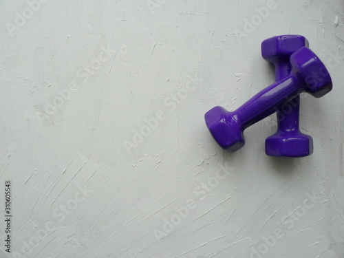 Purple dumbbells on a white textured background with space for your text.