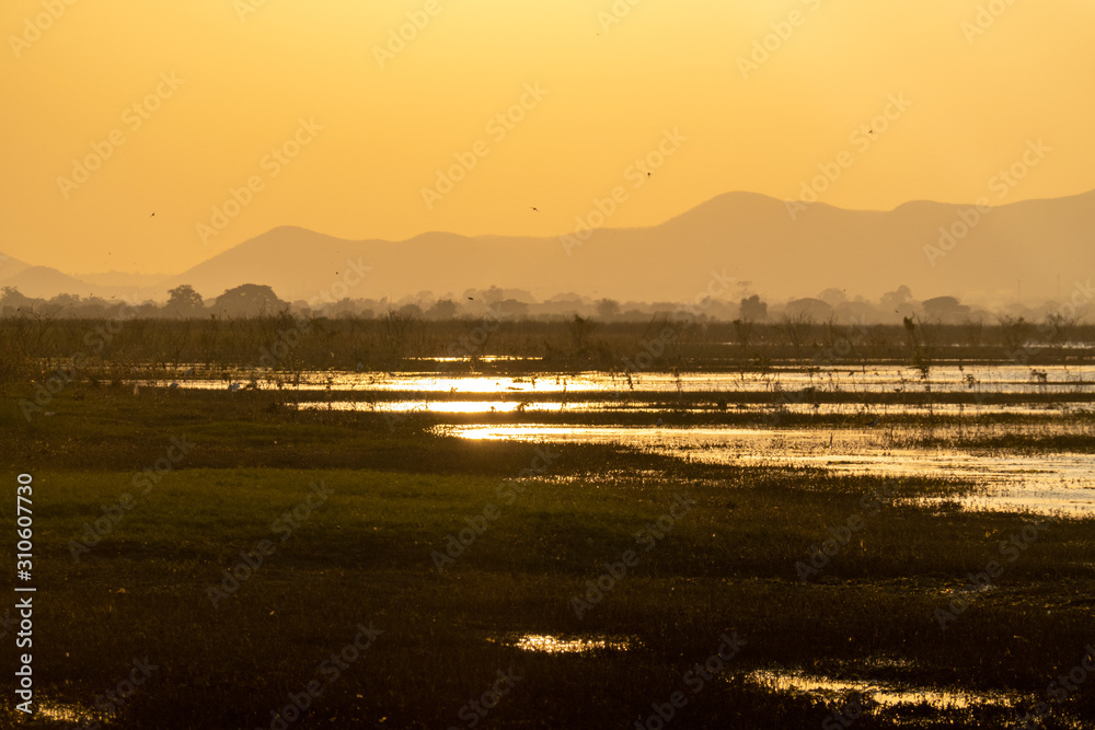 Fototapeta premium Sunset golden hour Peaceful sunset at small lake in Thailand with a mountain in the background.