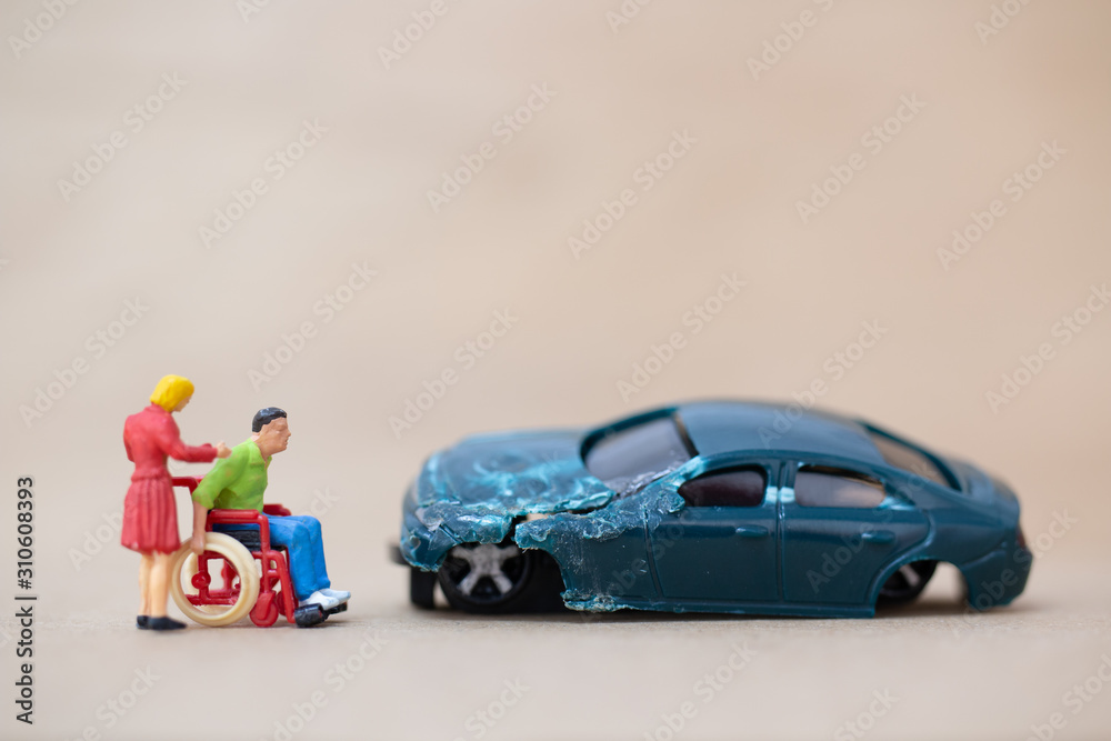 Fototapeta premium Miniature people : Disabled man sitting in wheelchair on on wooden background , Accident concept