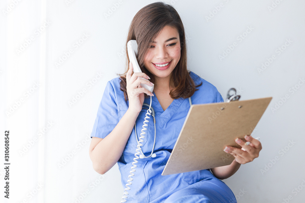 Asian woman in blue doctor uniform using telephone on white background Asian woman in blue doctor uniform using telephone on white background