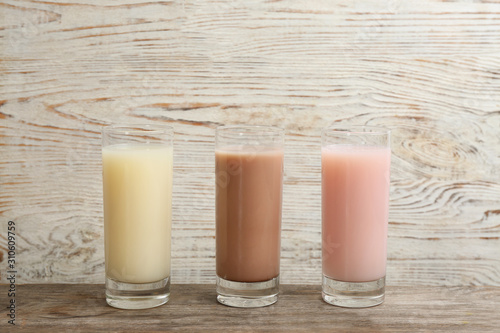 Different protein shakes in glasses on wooden table