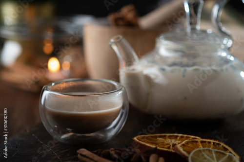 Milk spicy Indian tea Masala in a teapot with cinnamon  cloves and anise. Oriental tea ceremony on wooden background