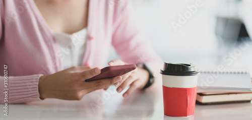 Close-up view of young businesswoman using smartphone with smartphone