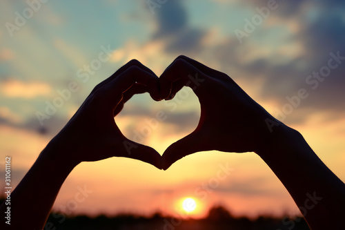 Love shape hand or Heart shaped silhouette at sunset background