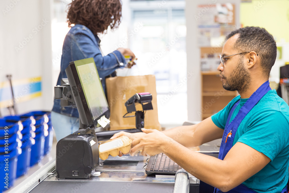 Male cashier scanning goods at checkout. Young woman with buying groceries in supermarket. Shopping concept Male cashier scanning goods at checkout. Young woman with buying groceries in supermarket. Shopping concept