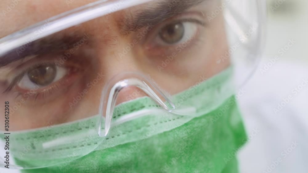 Close-up portrait of serious doctor or dentist in surgical mask looking to patient after anesthesia Close-up portrait of serious doctor or dentist in surgical mask looking to patient after anesthesia
