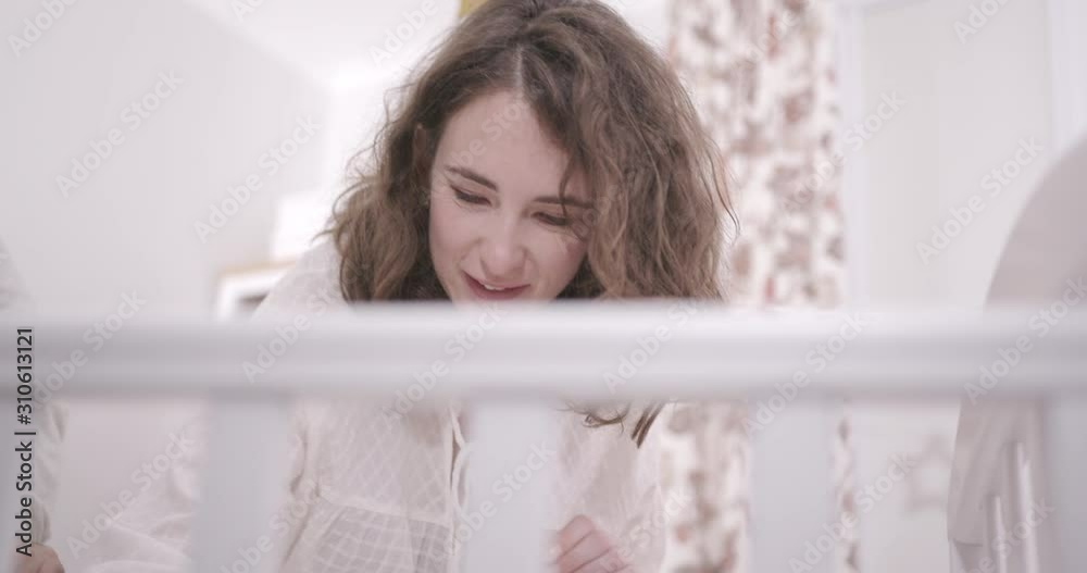 Young parents stand at the crib of a newborn baby. Concept of Family, Parenthood and Happiness Young parents stand at the crib of a newborn baby. Concept of Family, Parenthood and Happiness
